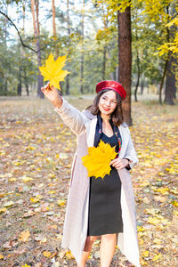 Portrait of young woman standing against trees