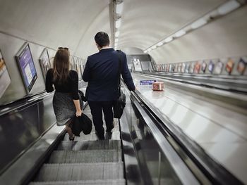 Rear view of people standing on escalator