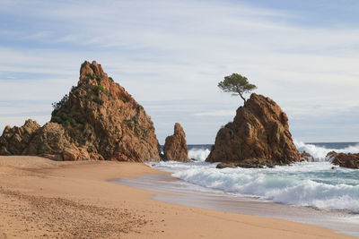 Rock formations on beach against sky