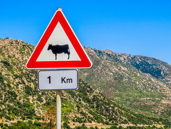 Close-up of road sign against clear blue sky