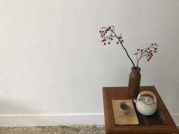 Close-up of flower vase on table against wall