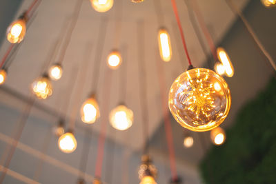 Low angle view of illuminated light bulbs hanging from ceiling