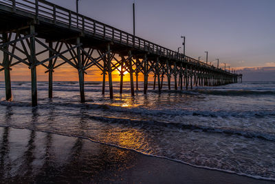 Pier over sea against clear sky during sunset