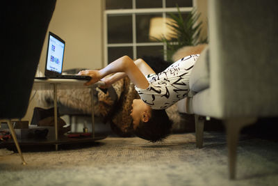 A 12-year old boy in an unusual body position uses a laptop computer
