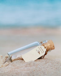 Close-up of bottle with wedding ceremony label on sand at beach