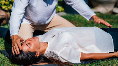 Close-up image of relaxed woman lying with her eyes closed and having reiki healing treatment 