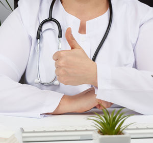 Midsection of doctor gesturing at desk in hospital