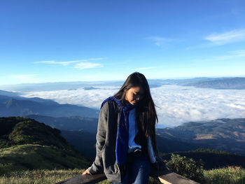 Young woman standing on mountain against sky
