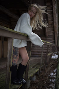 Side view of young woman standing by railing