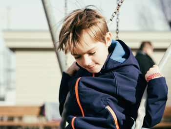 Boy playing on swing at playground