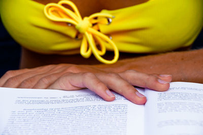 Midsection of seductive woman with book at home