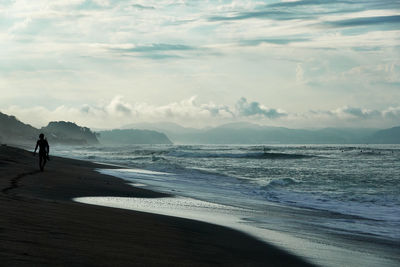 Man walking at sea against sky