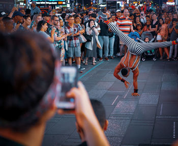 Rear view of people photographing on street in city