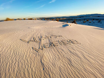 Footprints on sand at beach against sky