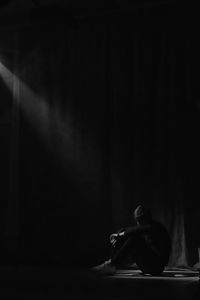 Full length of depressed man sitting in darkroom