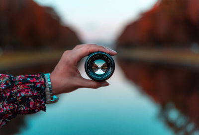 Close-up of hand holding lens against sky