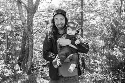 Portrait of happy boy standing by tree in forest