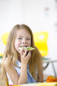 Portrait of a girl eating food on table at school