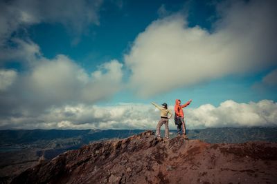 Men standing on rock against sky