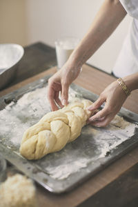 High angle view of woman preparing challah bread in tray at table