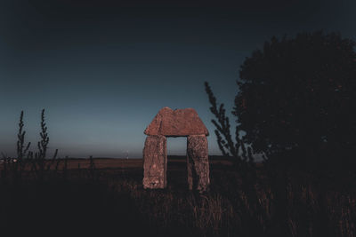 Old barn on field against clear sky at dusk