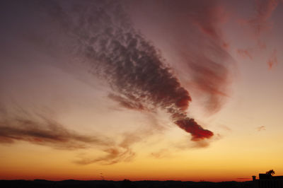 Silhouette vapor trail against sky during sunset