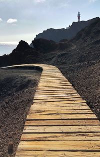 Footpath leading towards lighthouse against sky