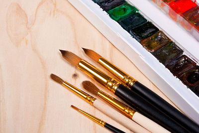 Close-up of paintbrushes and watercolor paints on table