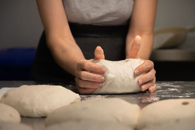 Women's hands carry out actions with raw bread. dough before dipping into a bakery oven