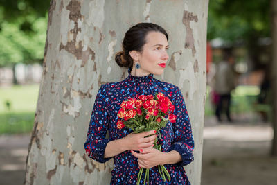 Portrait of pretty woman in a blue dress with bouquet of rose flowers