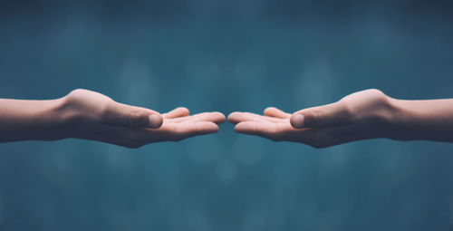 Close-up of hands against blue sky