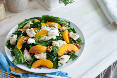 Top view plate with tasty peach and spinach salad on wooden table with copy space