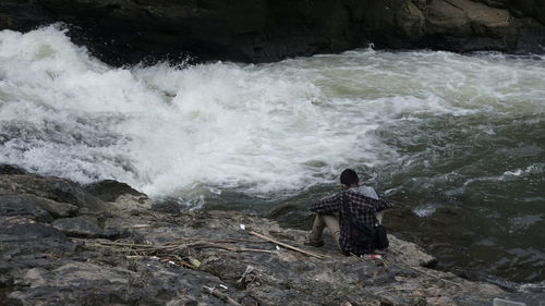 Man standing on rock by sea