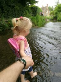 Young girl with pink back pack holding hand and walking in shallow water