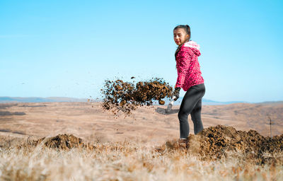 Young woman shoveling and digging a hole in the ground