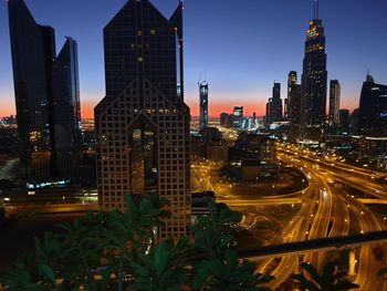 Illuminated modern buildings in city against sky at dusk