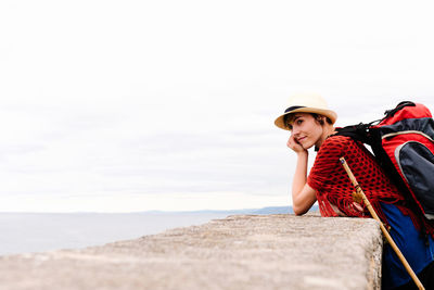 Portrait of young woman sitting against sky