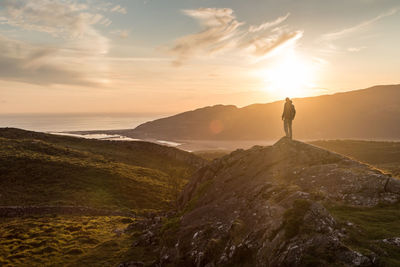 Man standing on mountain against sky during sunset