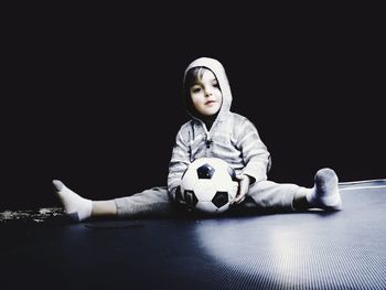 Portrait of cute boy with soccer ball sitting on floor