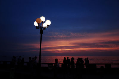 Silhouette people at beach against sky during sunset