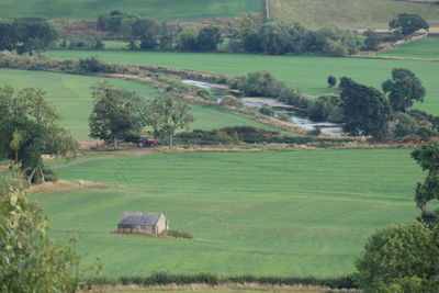 Scenic view in the sunshine of agricultural fields with a red tractor, next to river