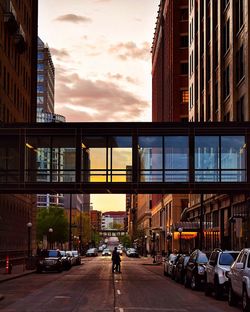 People on city street against sky during sunset