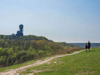 Rear view of young couple walking on teufelsberg mountain near berlin, germany