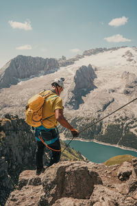 Man standing on rock against sky