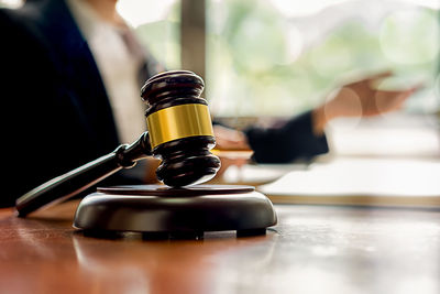 Close-up of gavel while judge sitting at table