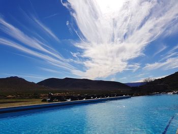 Scenic view of lake by mountains against blue sky