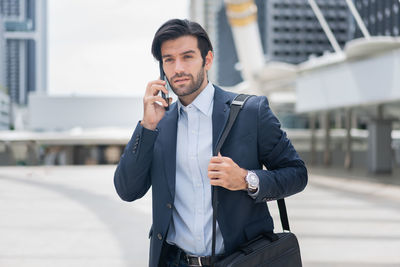 Portrait of businessman talking on mobile phone while standing in city