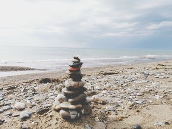 Stack of pebbles on beach against sky