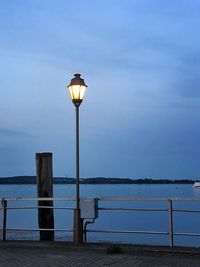 Street light by sea against sky at dusk