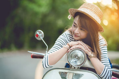Smiling mid adult woman relaxing on motor scooter at road